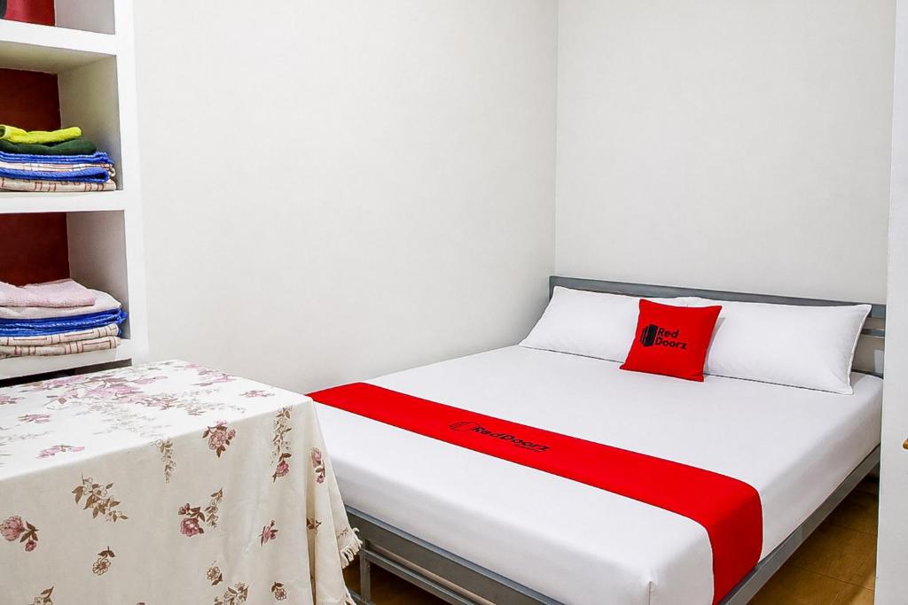 a small room with a bed with a red pillow at RedDoorz at Jatisampurna 