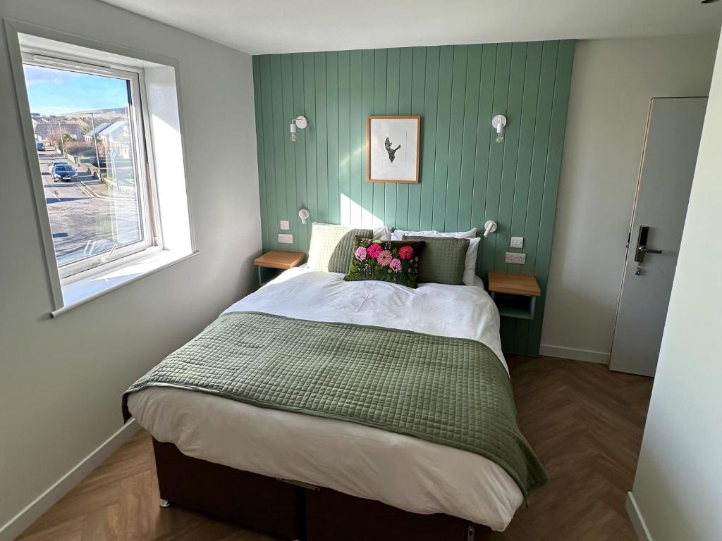 a bedroom with a bed with green walls and a window at Garden House Rooms in Kirkwall