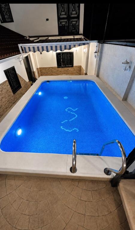 a large blue swimming pool in a room at Villa Wilecris in Punta Umbría