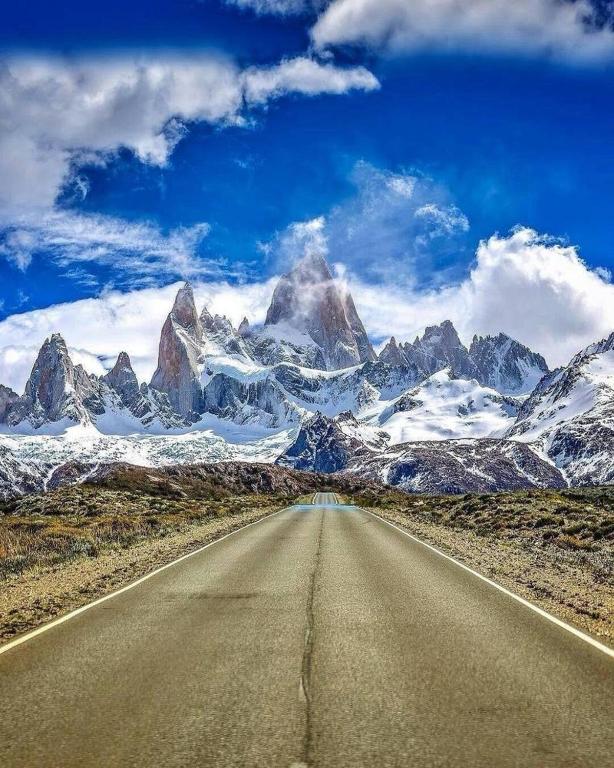 an empty road in front of a snow covered mountain at Sur Refugio de Montaña in El Chalten