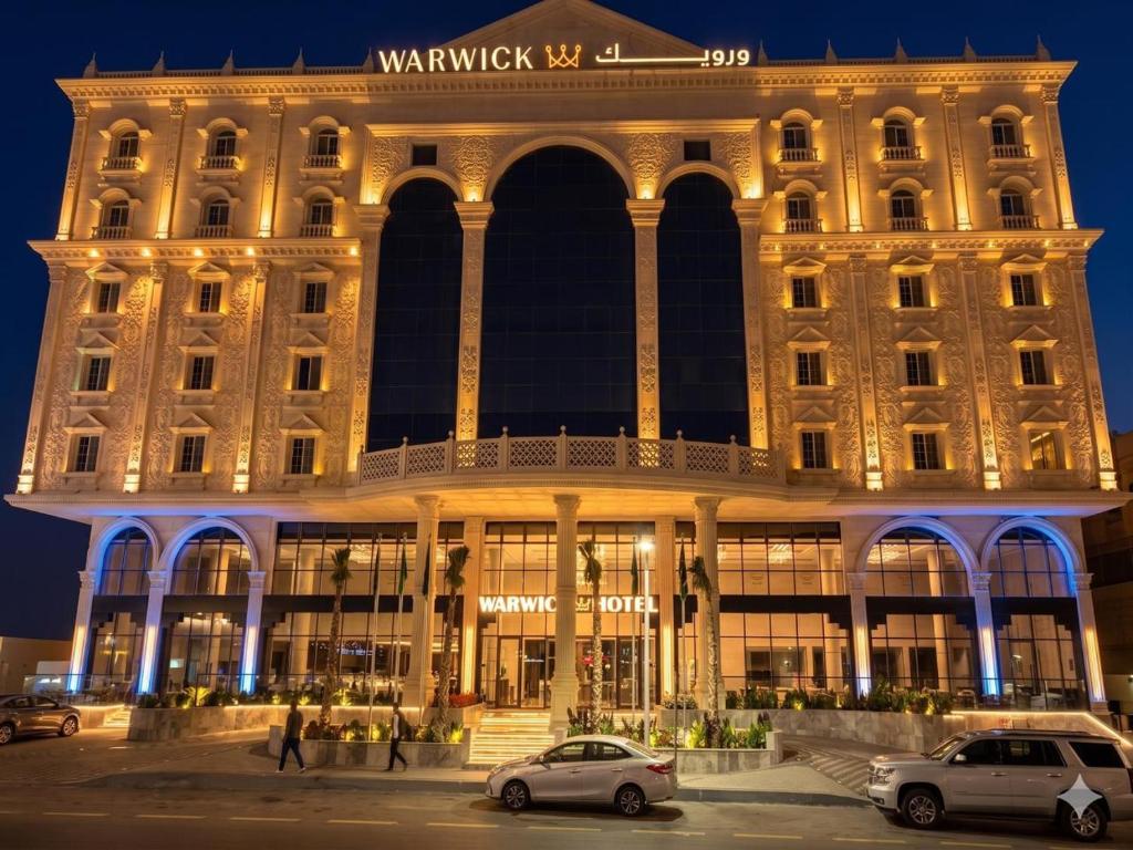 a large building with cars parked in front of it at Warwick Al Baha Hotel in Baljurashi