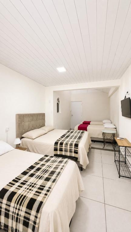 two beds in a room with white walls at Suíte próximo a BR! in São José