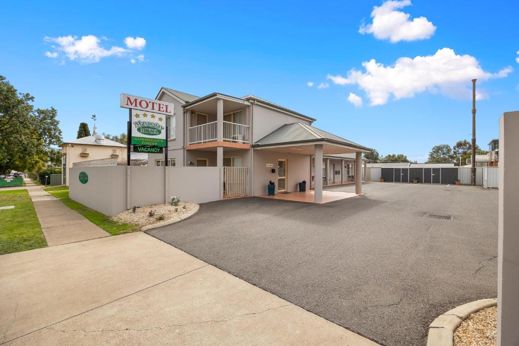 a building with a motel sign in a parking lot at Maynestay Motel in Gunnedah