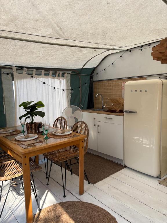 a kitchen with a table and a refrigerator in a tent at Przyczepa Kempingowa Beige in Jastarnia