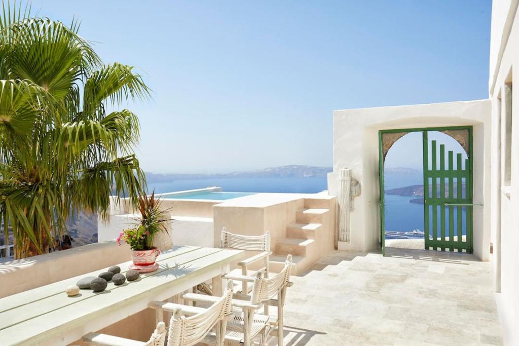 a patio with a table and chairs and the ocean at Villa Murat in Fira