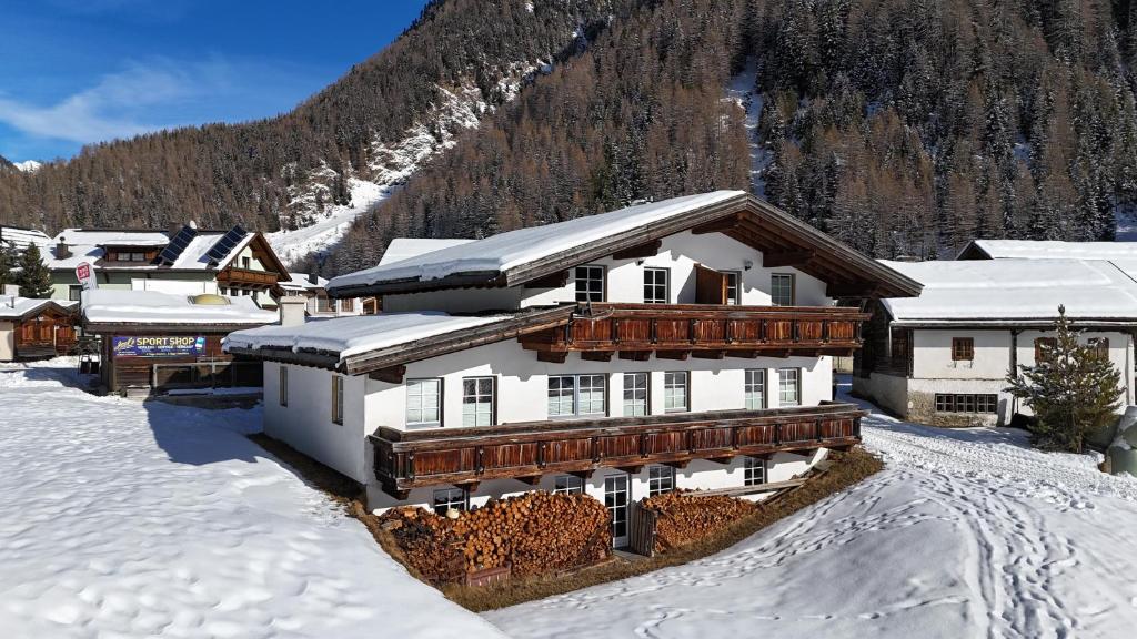 a building in the snow with a mountain in the background at Gipfelblick Appartements in Umhausen