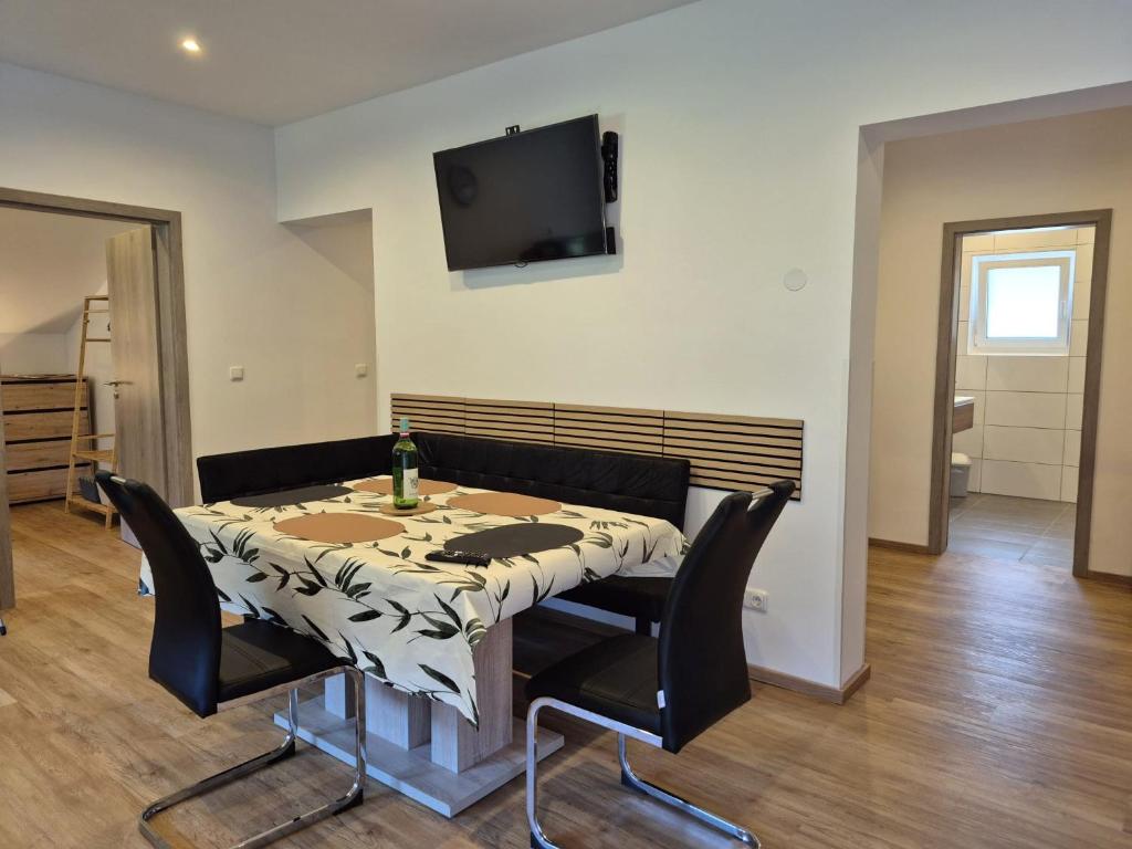 a dining room table with chairs and a television on the wall at Alie Gusta in Hermagor