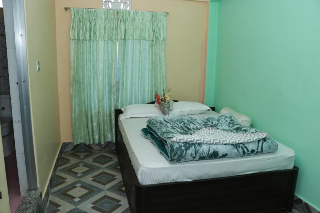 a bed in a room with a green curtain at Gauri Shanker Hotel and Lodge in Dharān Bāzār