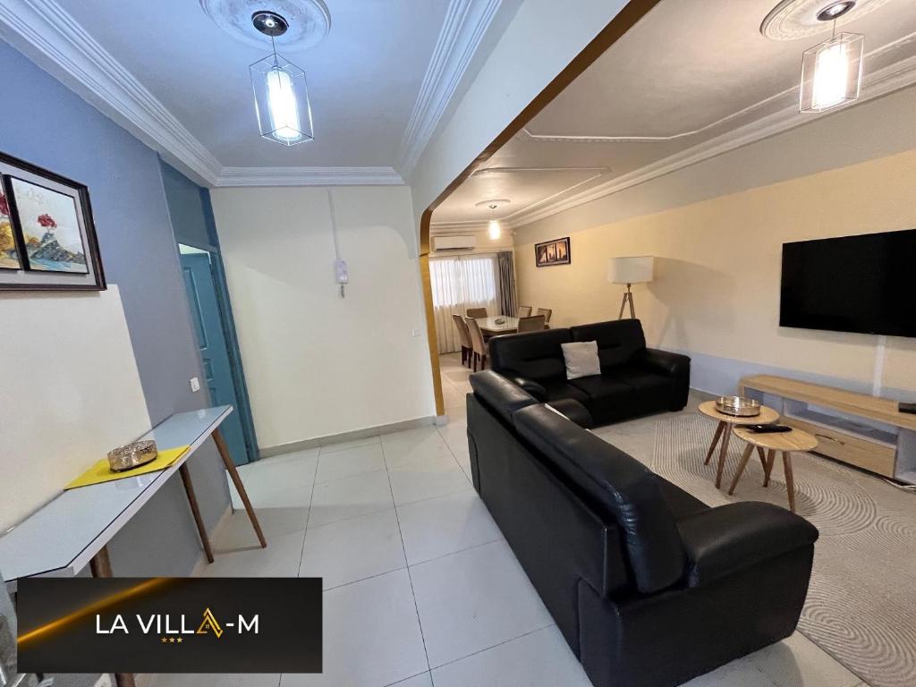a living room with a black couch and a tv at Villa M Douala Maison 3 Chambres Makepe in Douala