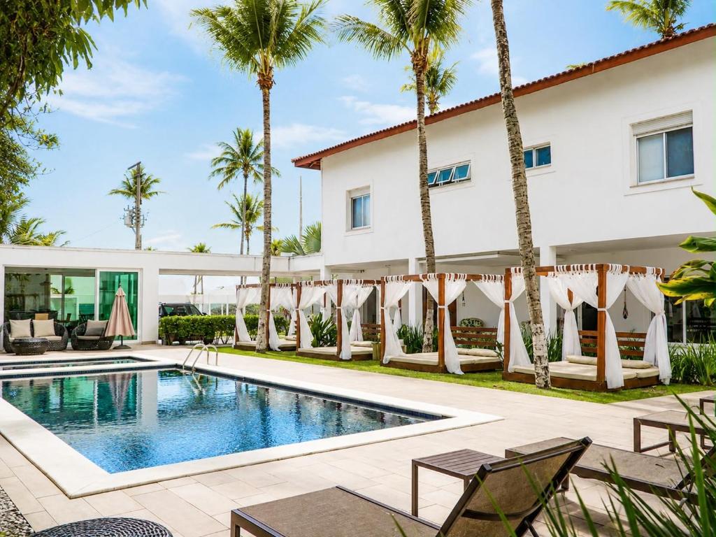 a villa with a swimming pool and palm trees at Makai Hotel Boutique - Frente Mar in Guarujá