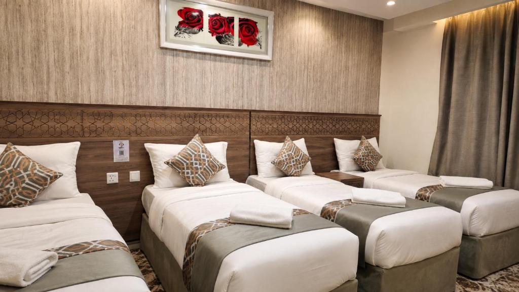 a row of beds in a room with red roses at فندق زهرة الفرسان in Mecca