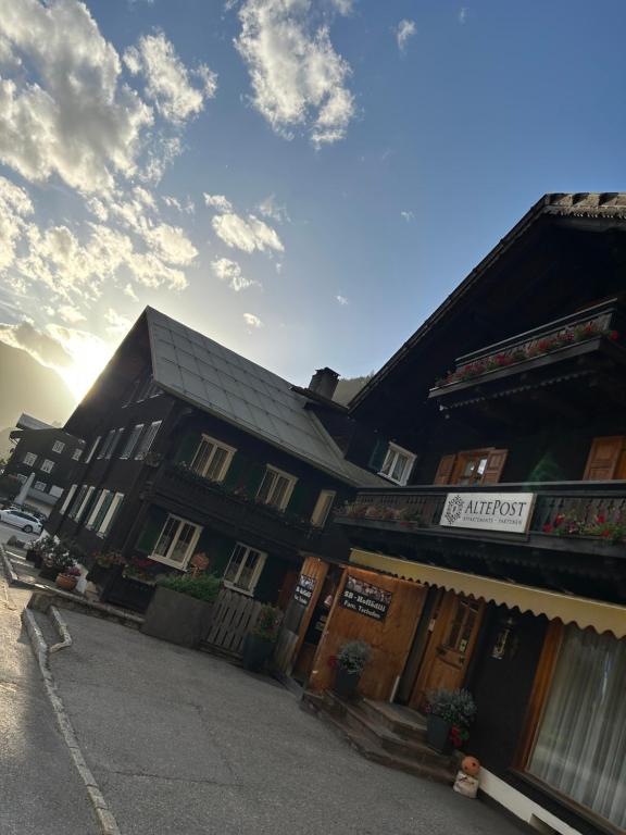 a building on a street with the sun in the background at Appart Alte Post in Partenen