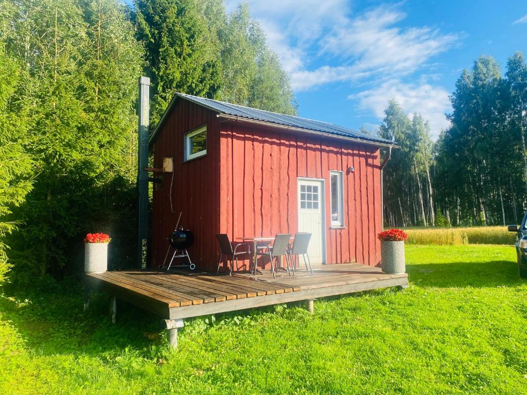 a red tiny house with a deck and chairs at Väikse haldja onn in Majala