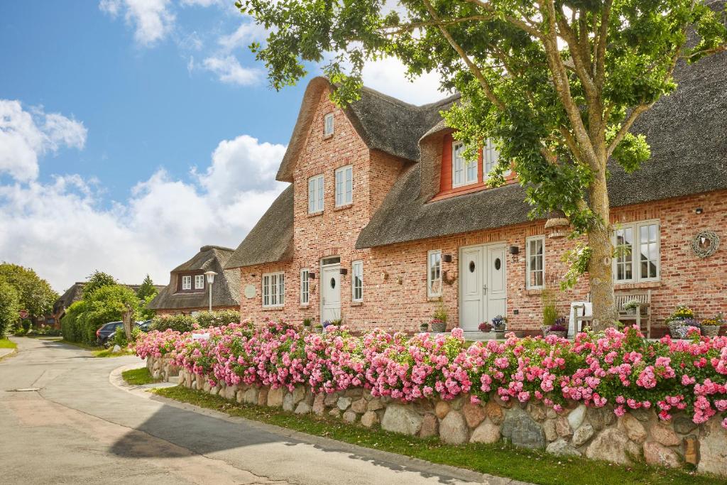 a brick house with pink flowers in front of it at Reethaus Nordgold in Oldsum