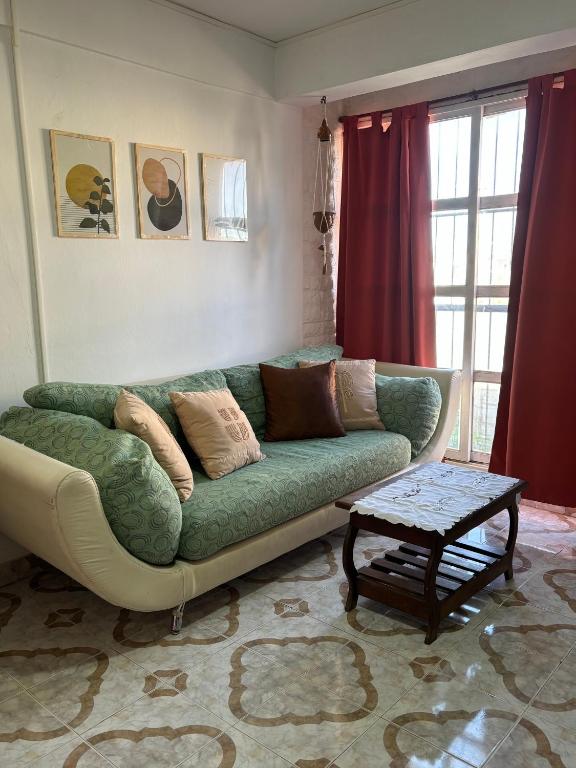 a living room with a green couch and a table at Depto hube in La Banda