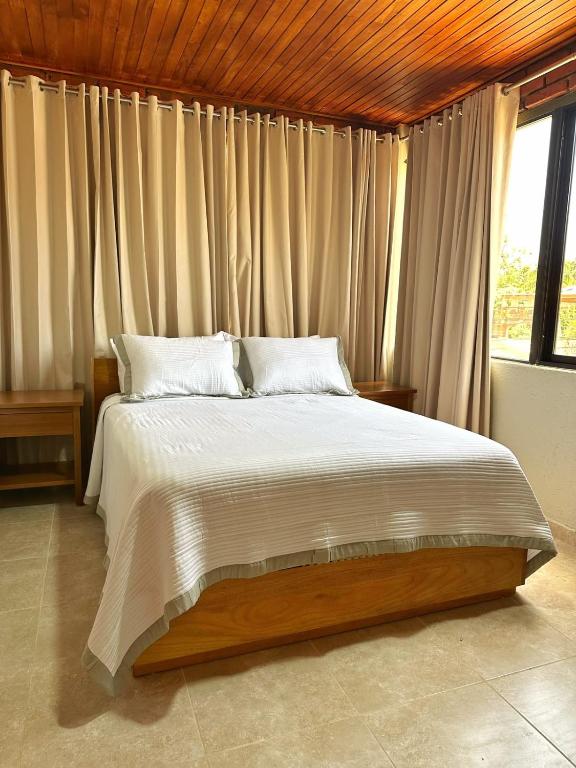a bedroom with a large bed in front of a window at Altura525 hotel in Jarabacoa
