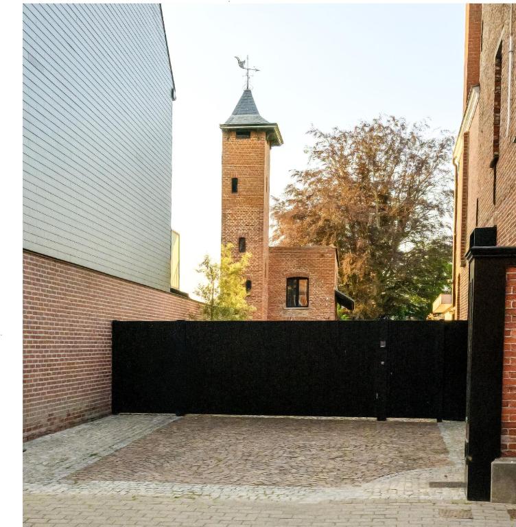 a brick building with a clock tower behind a fence at Aplusstudio in Zottegem