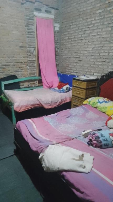 a room with three beds with pink sheets and a dresser at Mini outlit in Puloasem