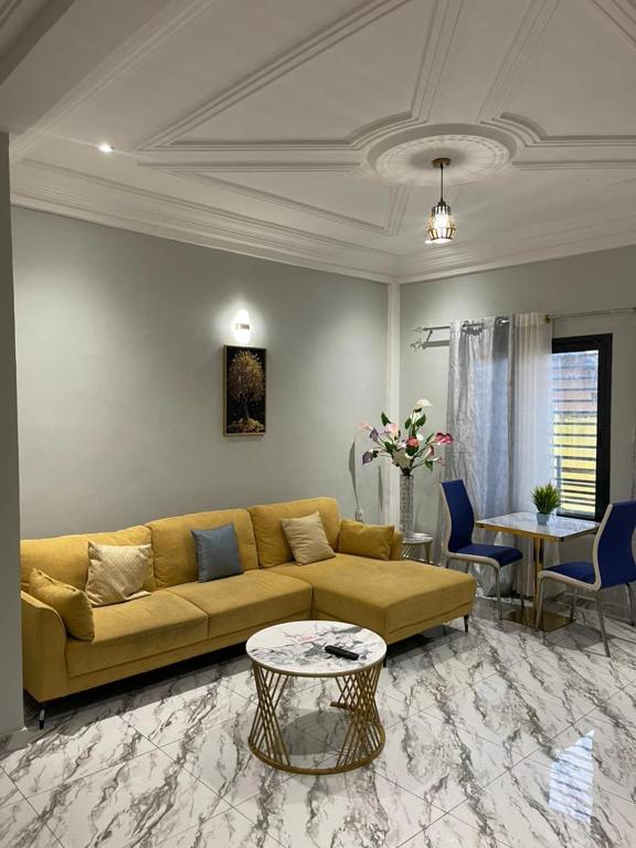 a living room with a yellow couch and a table at At Home Bertoua in Bertoua