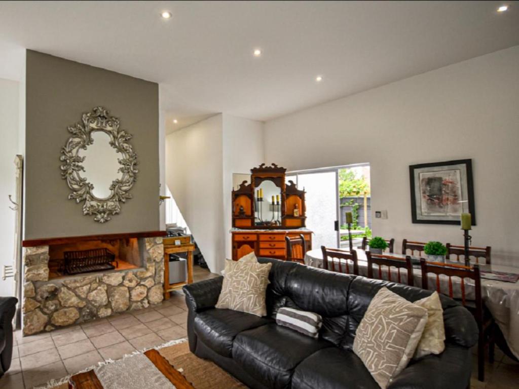 a living room with a black leather couch and a fireplace at Lieflappie Seaview Stilbaai 400m to the beach in Stilbaai