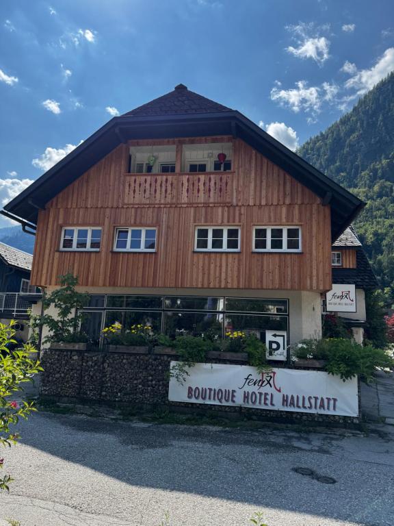 a large wooden building with a sign in front of it at Fenix Hall Boutique Hotel Hallstatt in Hallstatt