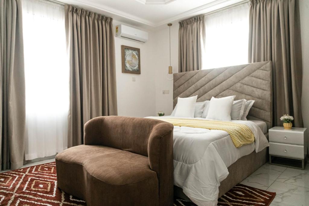 a bedroom with a large bed and a chair at Sunrise Cave in Oyibi