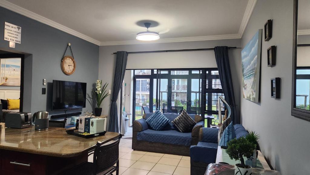 a living room with a blue couch and a tv at Topanga 17 in Uvongo Beach