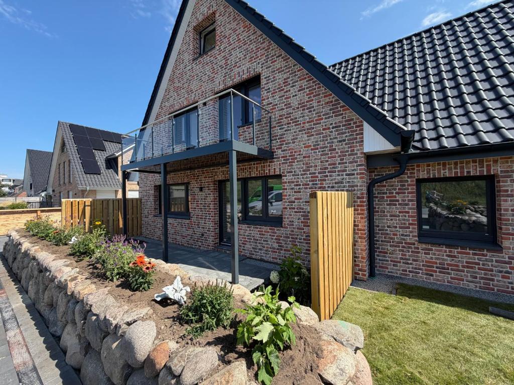 a brick house with a stone retaining wall at BeachHus 35, Whg 4 in Sankt Peter-Ording