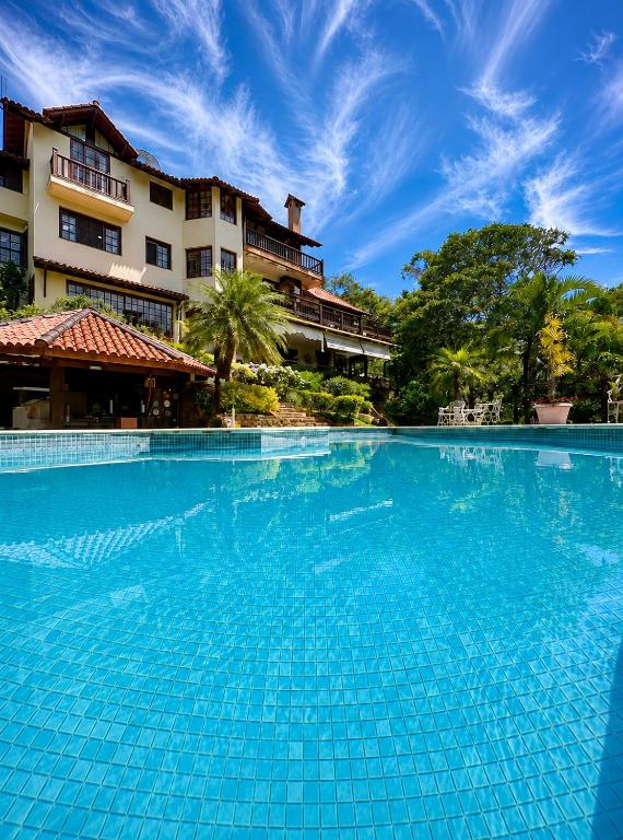 a large blue swimming pool in front of a building at Chalé Guararema in Petrópolis