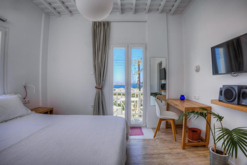 a hotel room with a bed and a desk and a window at Gazia Sea View House - Mykonos Town in Mikonos