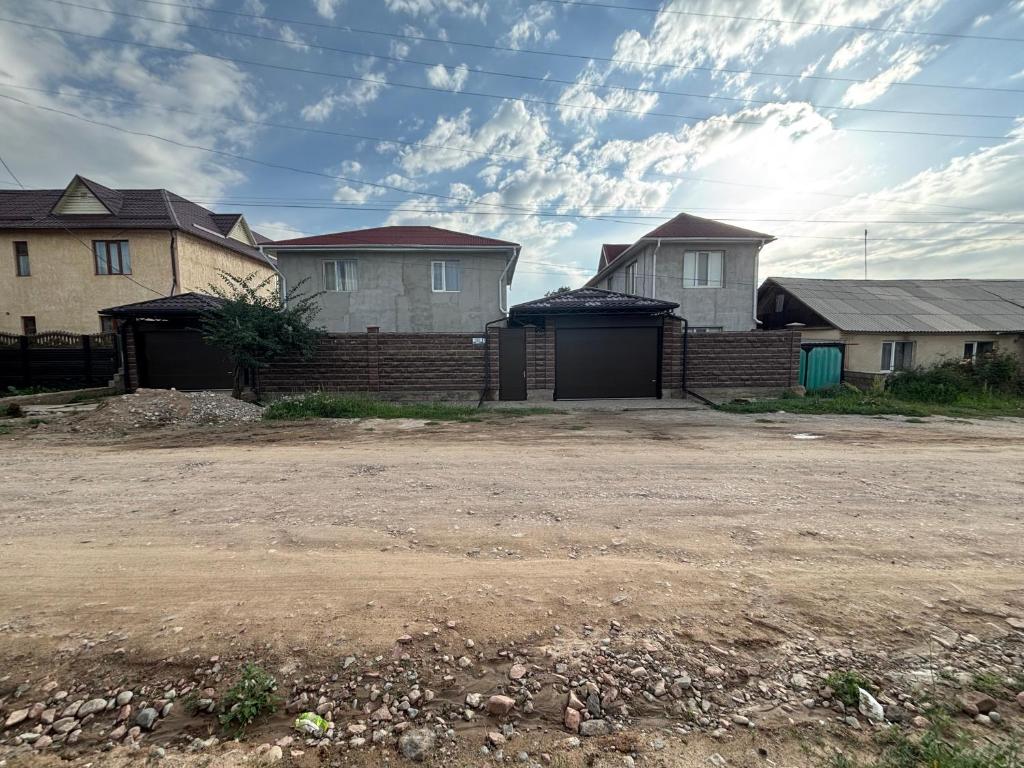 a row of houses with a dirt road in front at Rinat Guest House in Pokrovka