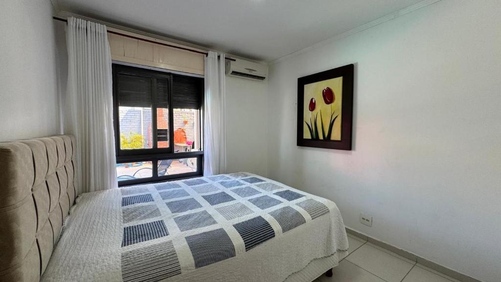 a bedroom with a bed and a window at Quarto Aconchego in Guaratuba