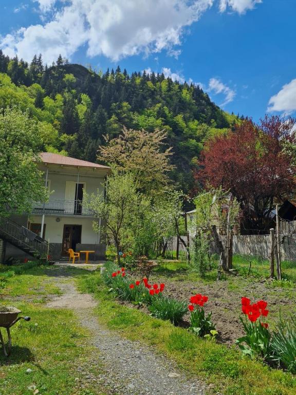 a house with red flowers in front of a mountain at Lentexi Inn in Lentekhi