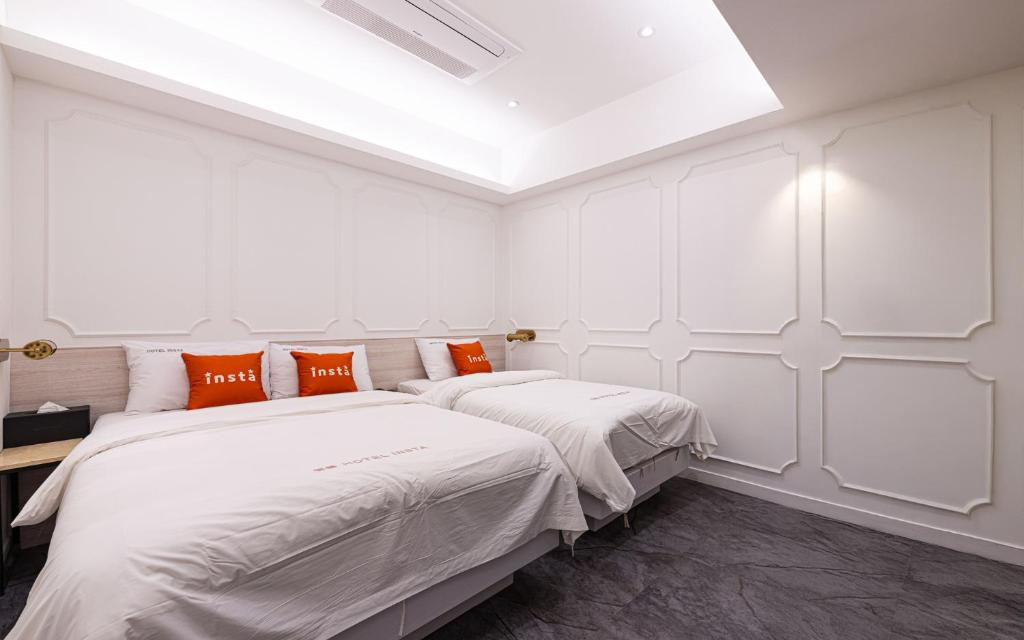 two beds in a white room with orange pillows at Instar Hotel in Suwon