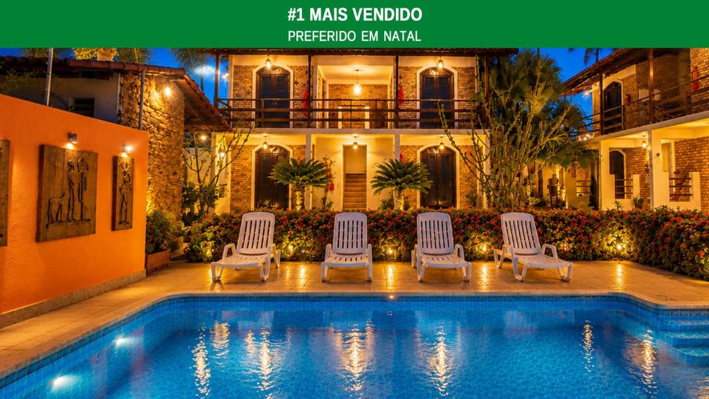 a swimming pool with four chairs and a house at Hotel Natal Ponta Negra Sun in Natal