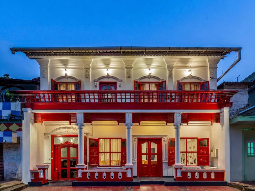 a white building with red doors and a balcony at Hope Hostels, Fort Kochi in Fort Kochi