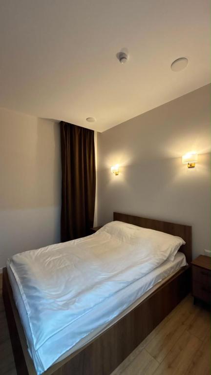 a bedroom with a bed with white sheets and a window at next green in Makhinjauri