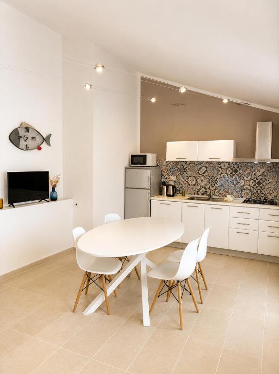 a white kitchen with a white table and chairs at Residence Borgo Punta Villa in La Maddalena