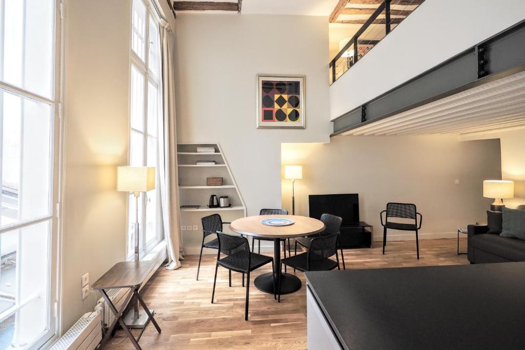 a living room with a table and chairs and a couch at Molière ChicSuites in Paris