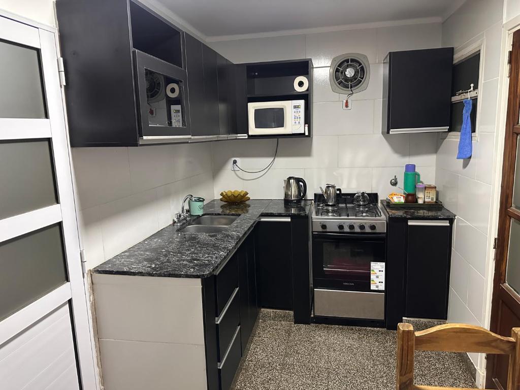 a small kitchen with black cabinets and a stove at French in Tres Arroyos