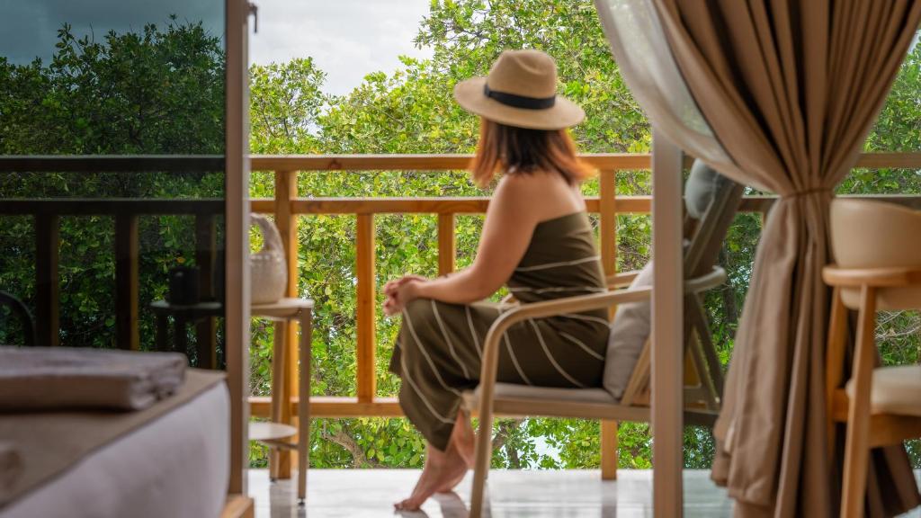 Eine Frau mit Hut sitzt auf einem Balkon in der Unterkunft WaterCloud Mathiveri in Insel Mathiveri