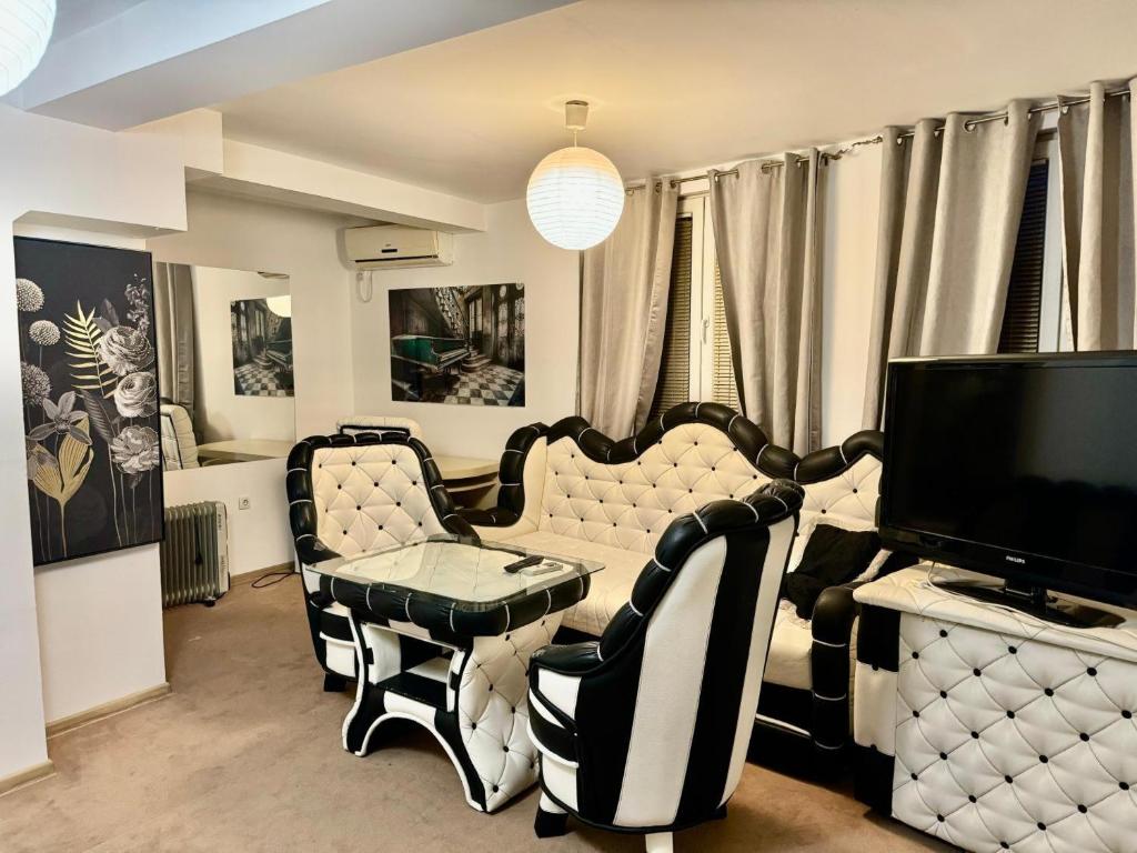 a living room with black and white furniture and a tv at Faraon apartmani Beograd in Belgrade