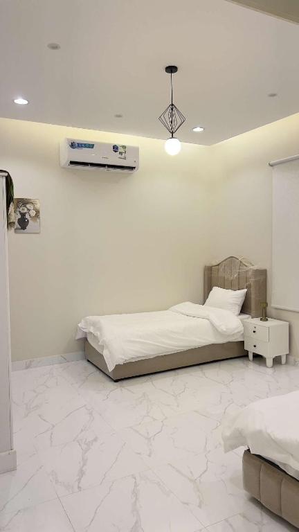 a white bedroom with a bed and a white wall at شاليهات الورد الفندقية in Ash Shuqayq