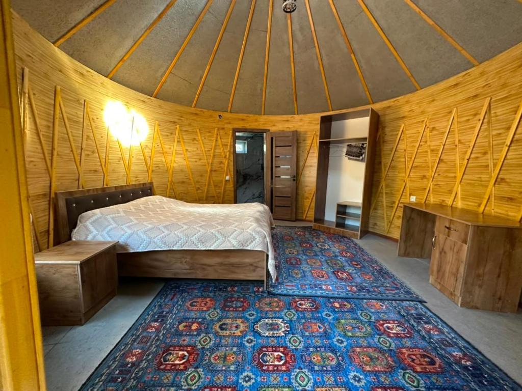 a bedroom with a bed and a rug in a room at Датка in Arslanbob