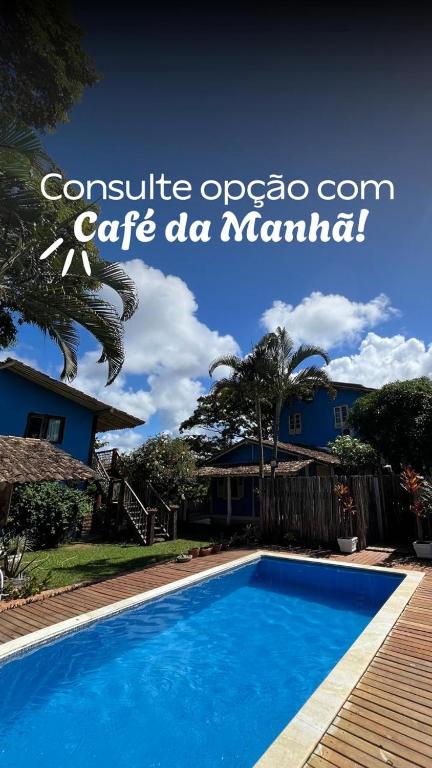 a blue swimming pool in front of a house at Vila Cizinho in Itaúnas