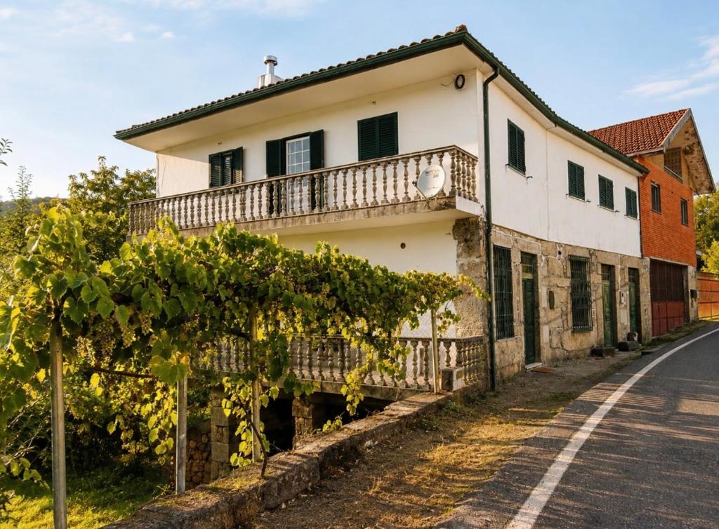 an old house with a balcony on the side of a road at Casa Misarela in Ruivãis