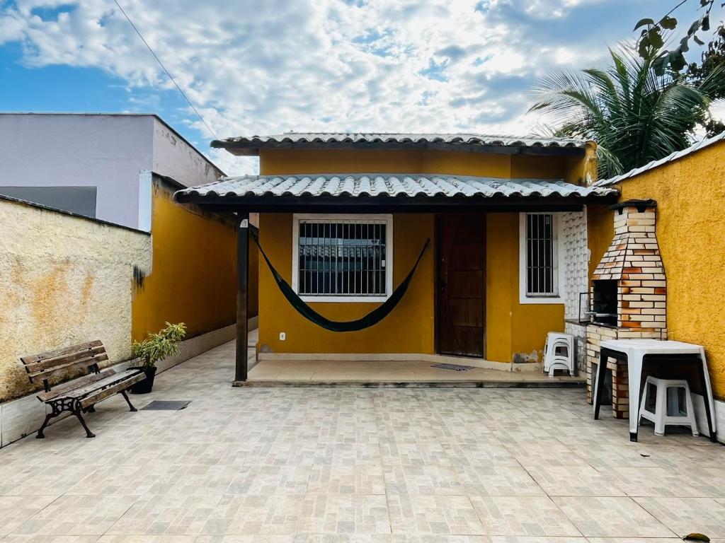 a yellow house with a bench in front of it at Casa Amarela de Praia in Maricá