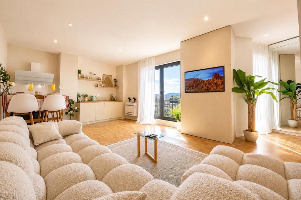 a living room with a large couch and a kitchen at Green Terrace Square View in Tirana