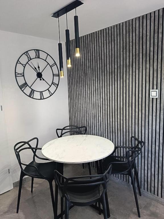 a table and chairs with a clock on a wall at Graphite Residence Chynowo in Chynowo