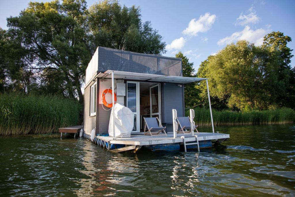 a tiny house on a dock in the water at Houseboat Dąbrowica in Dąbrowica